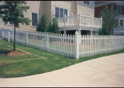 The angular view of whitewashed fencing around a beige house