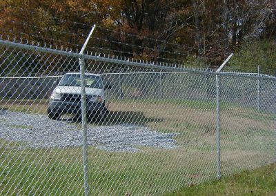 Meshed tall metal fencing with barbed wire