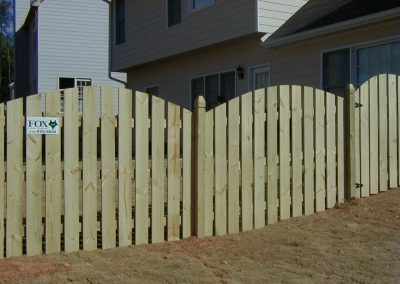 A panel of wooden plank fencing with a rounded top design