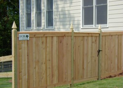 A straight wooden fencing around a white house