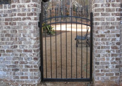 A metal gate attached to brick walls