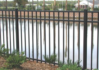 A plain straight black metallic fencing around a waterbody