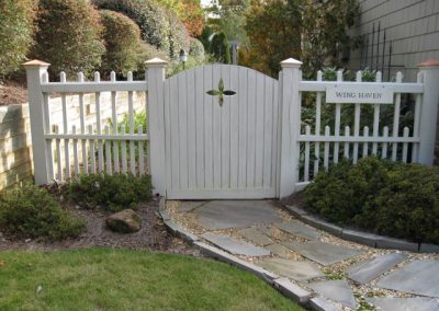 A white wood plank fencing and no gap gate with a flower pattern